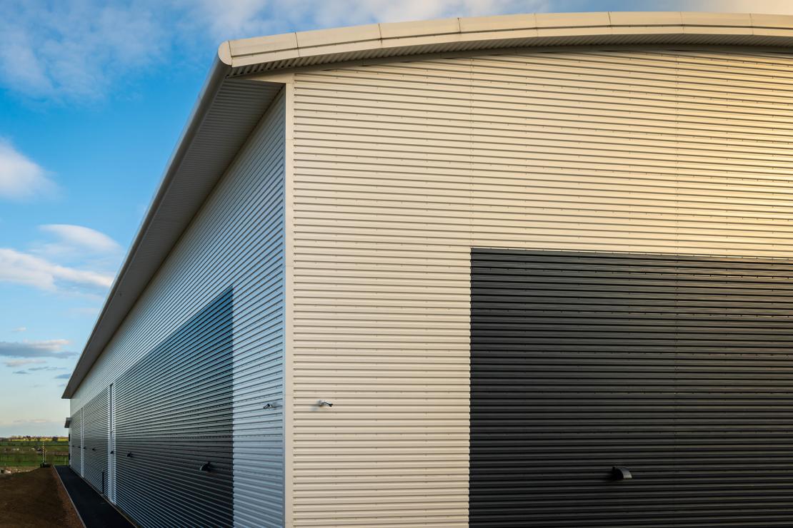 Modern steel-clad industrial warehouse with large roller shutter doors, representing commercial property investment through SIPP or SSAS